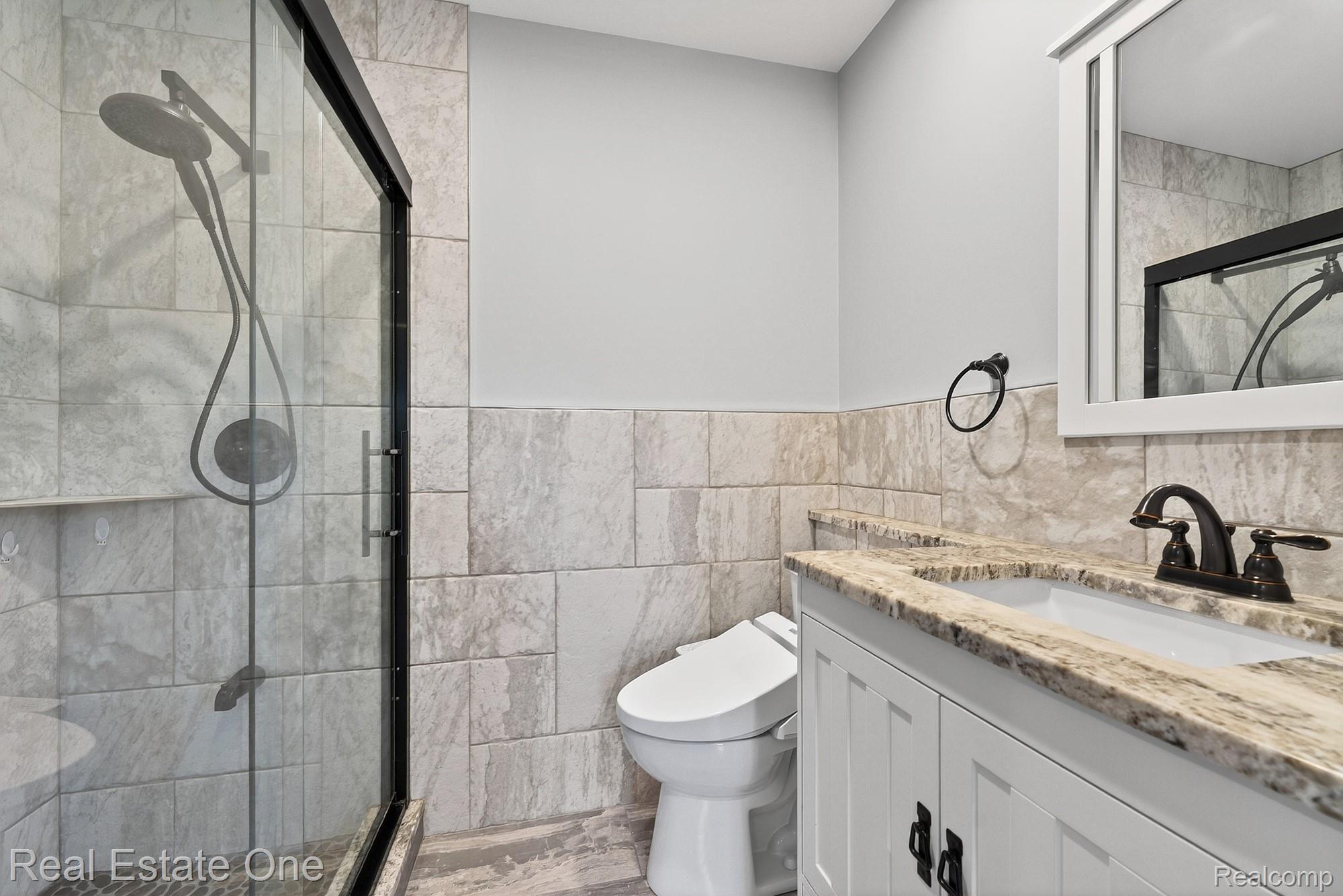 26987 Crawford Road Romulus, MI 48174 - Photo 19 of 51 Bathroom featuring a glass-enclosed shower with pebble flooring and a built-in shelf