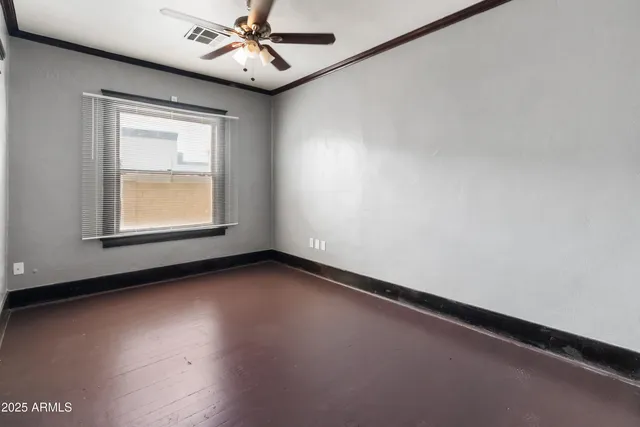 an empty room with chandelier fan and windows