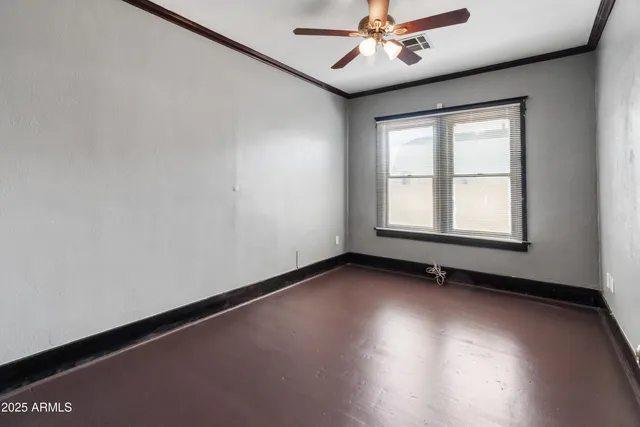 an empty room with a ceiling fan and wooden floor