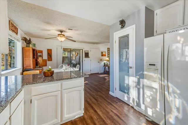 a living room with stainless steel appliances furniture wooden floor and a kitchen view