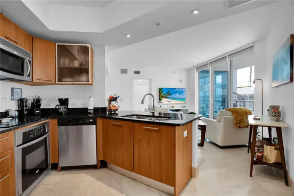 a kitchen with stainless steel appliances granite countertop a stove top oven a sink dishwasher and white cabinets with wooden floor