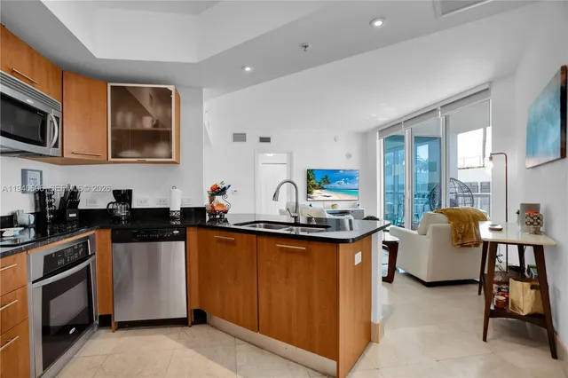 a kitchen with stainless steel appliances granite countertop a stove top oven a sink dishwasher and white cabinets with wooden floor