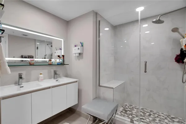 a bathroom with a double vanity sink mirror and shower