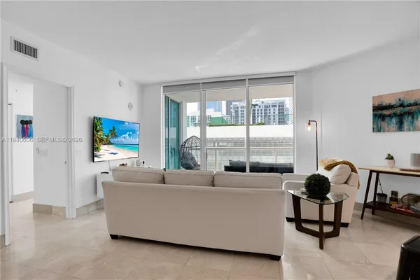 a living room with furniture a flat screen tv and a large window
