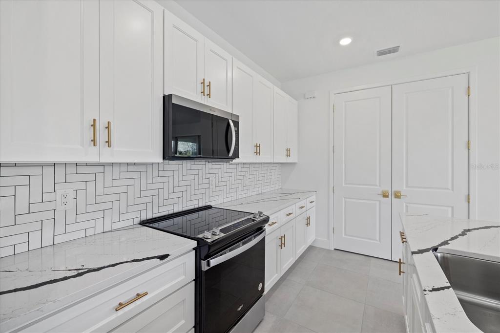 7443 South Seagrape Road Punta Gorda, FL 33955 - Photo 10 of 44 a kitchen with granite countertop white cabinets and black appliances