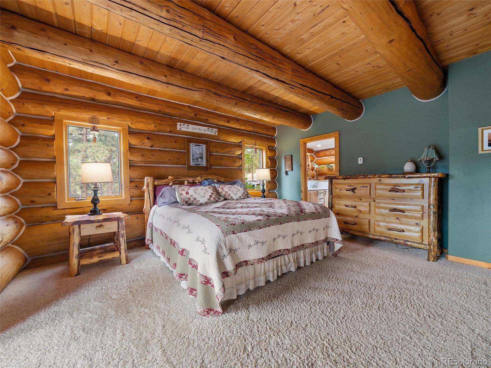 96 Six Bits Street Bailey, CO 80421 - Photo 21 of 40 a spacious bedroom with a bed and a chandelier