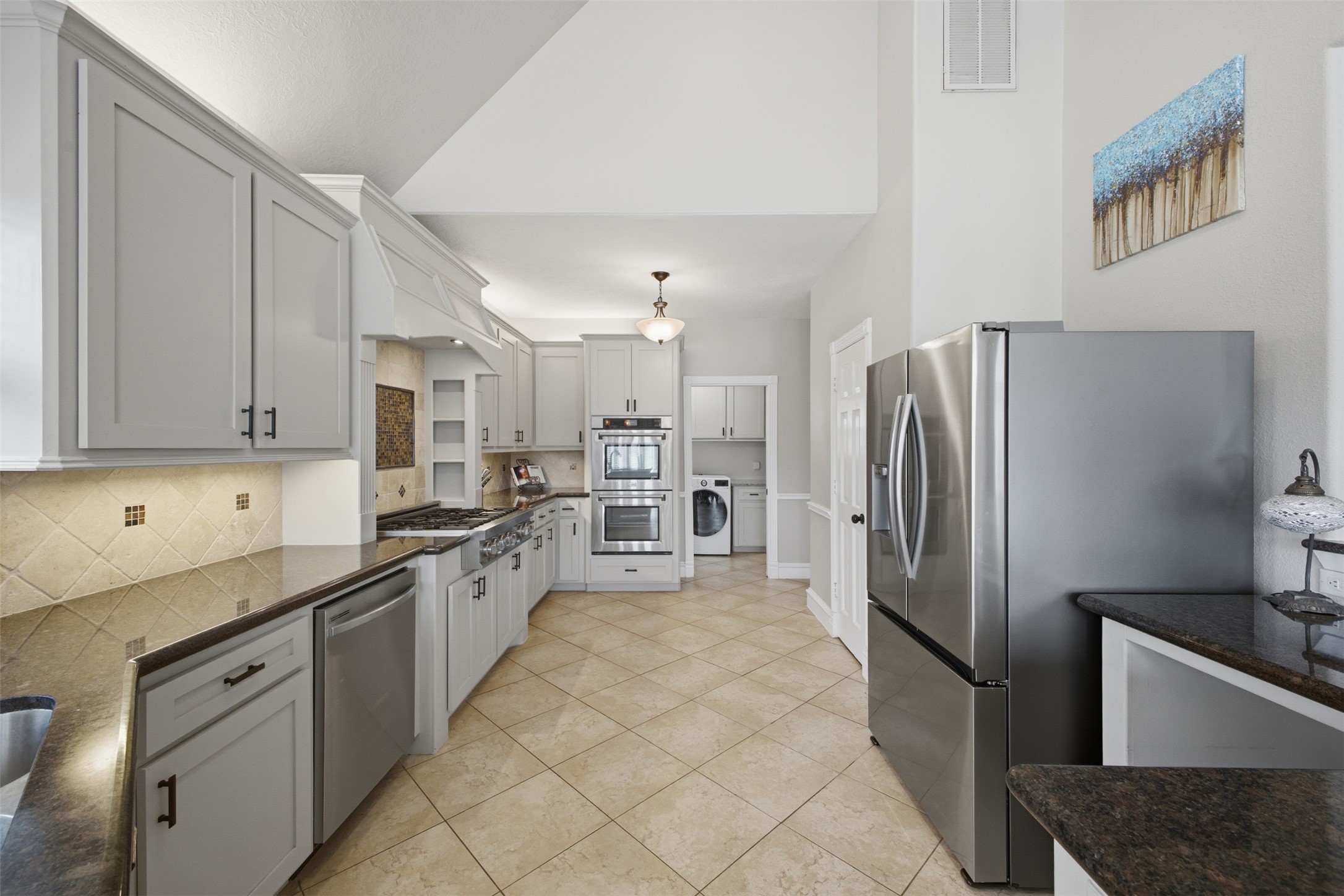 12710 Aries Loop Willis, TX 77318 - Photo 12 of 40 The kitchen features light-colored cabinetry with dark hardware, dark countertops, and stainless steel appliances including a refrigerator, dishwasher, and double oven