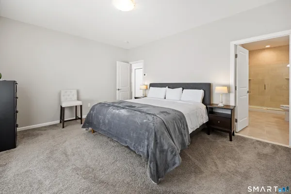a spacious bedroom with a bed and a lamp