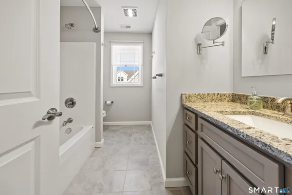 a bathroom with a granite countertop sink a mirror and shower