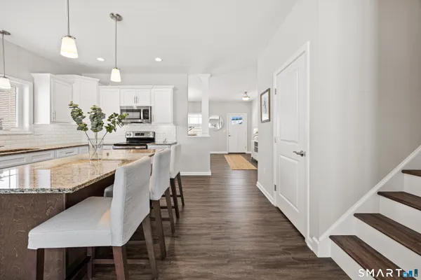 a kitchen with kitchen island a dining table chairs stainless steel appliances and cabinets