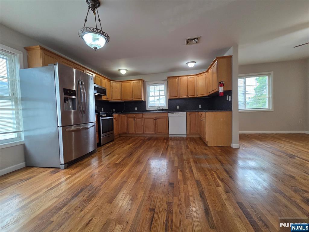 22 Broadway, Unit 2 Hackensack, NJ 07601 - Photo 3 of 11 a kitchen with stainless steel appliances wooden floor and refrigerator