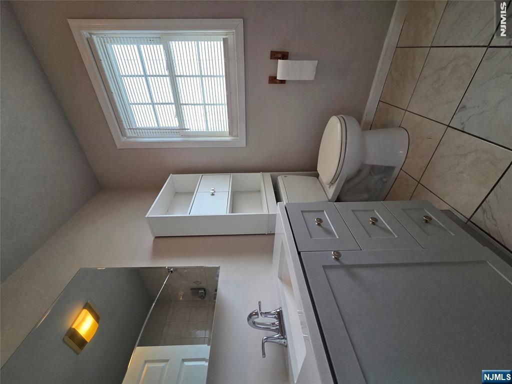 22 Broadway, Unit 2 Hackensack, NJ 07601 - Photo 9 of 11 a spacious bathroom with a toilet a sink a mirror and a window