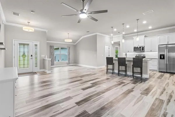 a view of a kitchen with stainless steel appliances refrigerator dining table chairs and a stove top oven