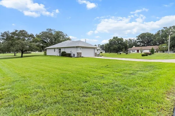 a view of a house with a big yard and large trees