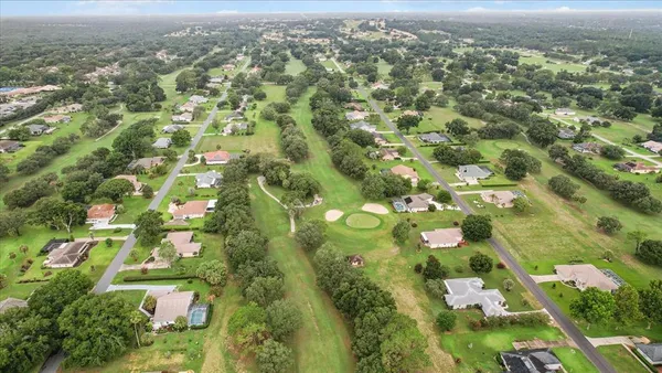 an aerial view of residential houses with outdoor space and trees
