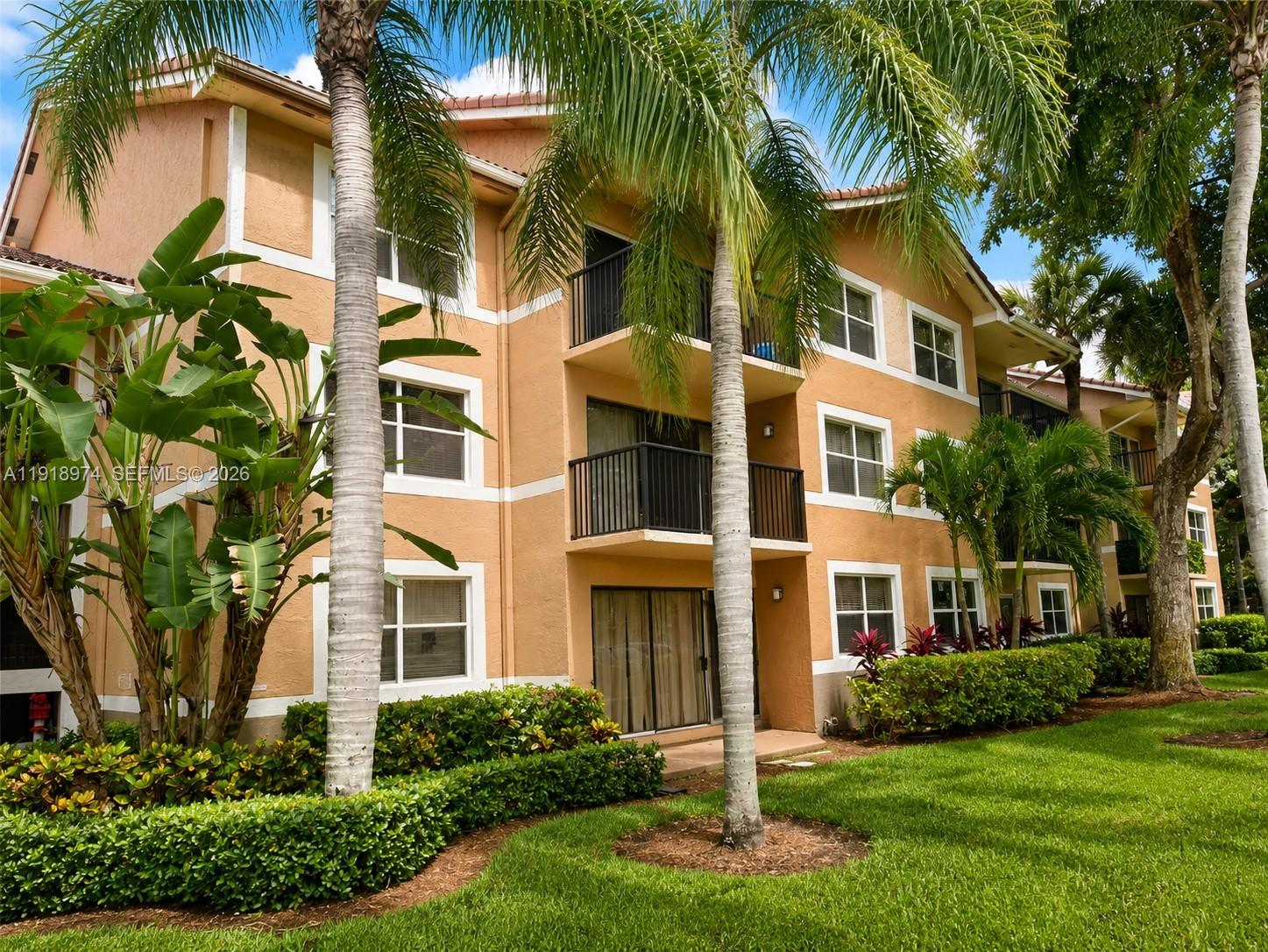8801 Wiles Road, Unit 307 Coral Springs, FL 33067 - Photo 5 of 18 a front view of a residential apartment building with a yard and palm trees