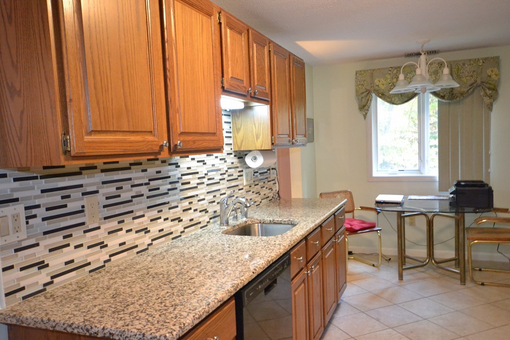 9 Ledgewood Way, Unit 2 Peabody, MA 01960 - Photo 7 of 22 a kitchen with a granite countertop sink and cabinets