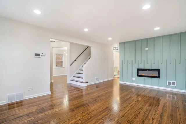 a view of an empty room with wooden floor and stairs