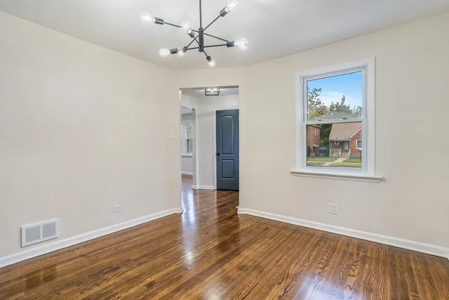 a view of an empty room with wooden floor and a ceiling fan