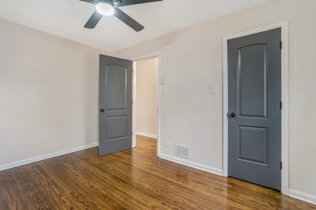 an empty room with wooden floor closet and ceiling fan