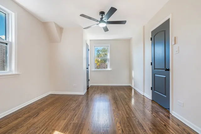 an empty room with wooden floor closet and windows