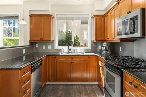 a kitchen with granite countertop stainless steel appliances a sink window and cabinets