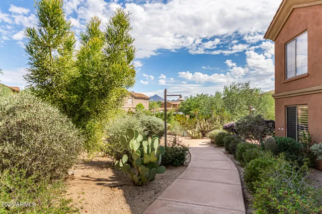 a view of a pathway with flower garden in front of it