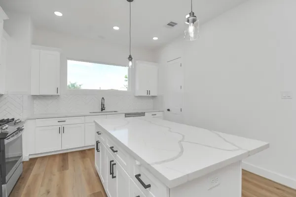 a kitchen with a sink dishwasher and white cabinets with wooden floor