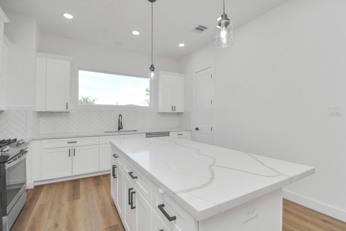 3036 Live Oak Street Houston, TX 77004 - Photo 17 of 35 a kitchen with a sink dishwasher and white cabinets with wooden floor