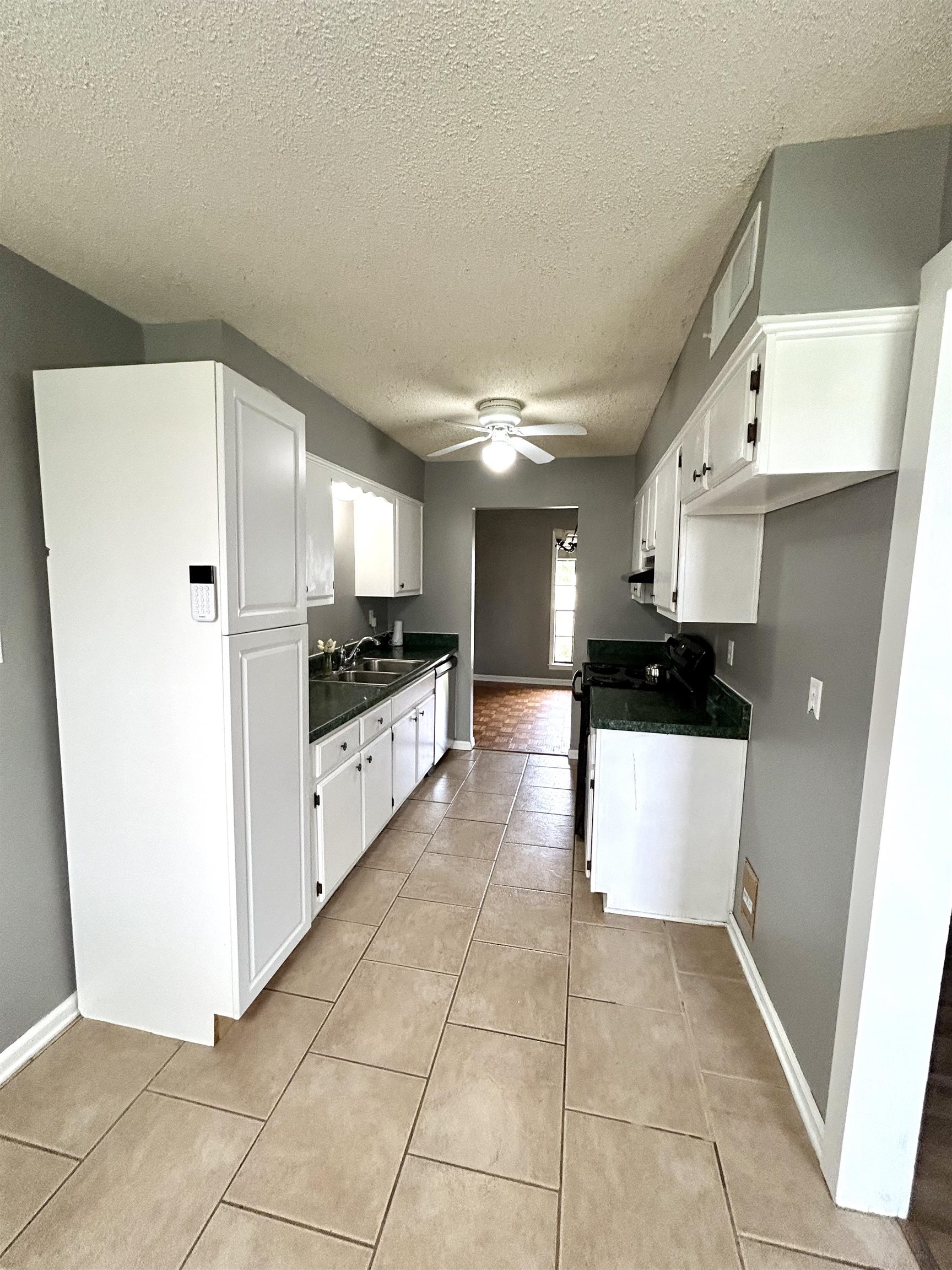 3257 Altruria Road Bartlett, TN 38134 - Photo 11 of 27 Kitchen with white cabinetry, a ceiling fan, a textured ceiling, light tile patterned flooring, and dark countertops