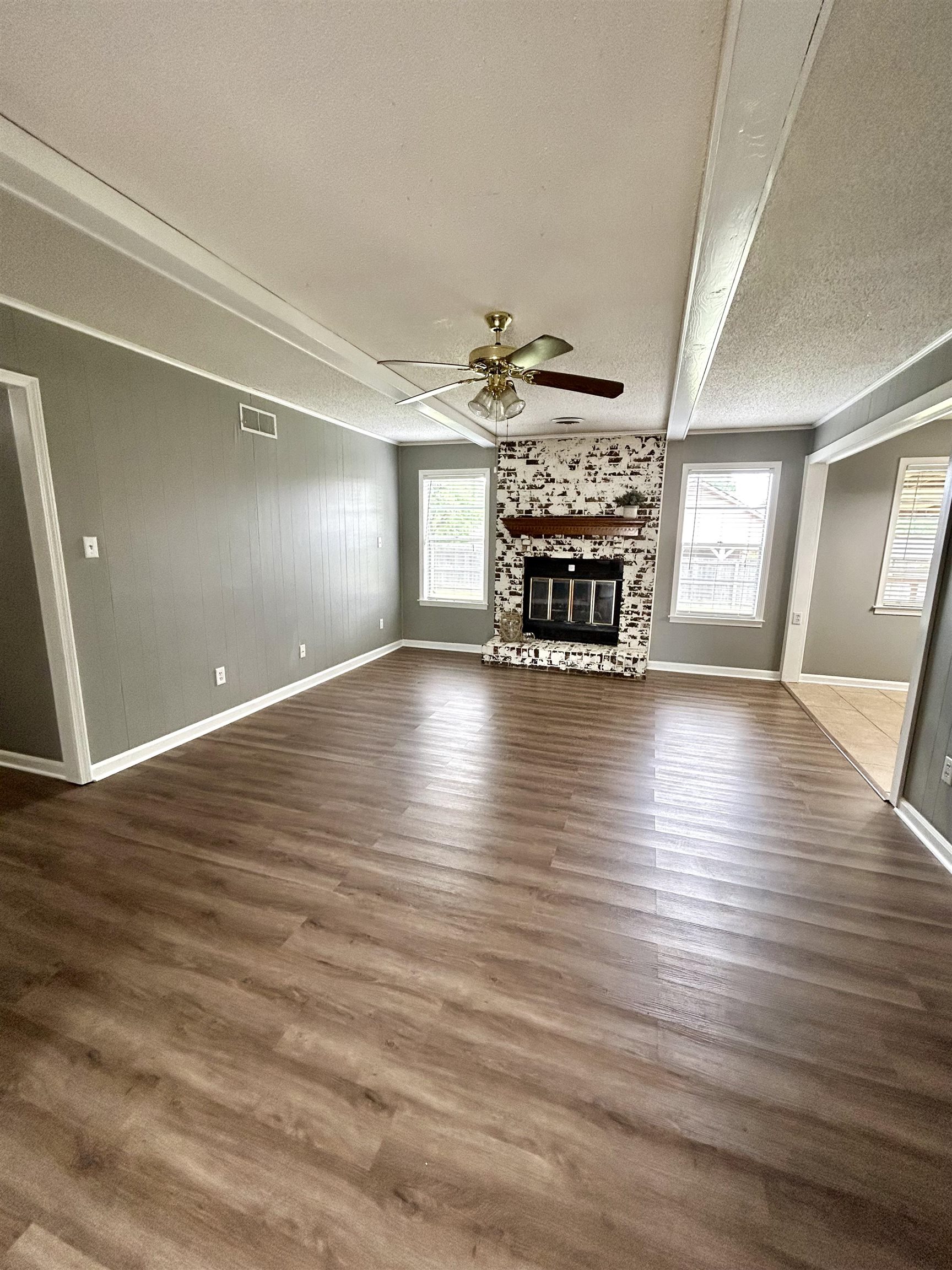 3257 Altruria Road Bartlett, TN 38134 - Photo 5 of 27 Unfurnished living room featuring a ceiling fan, baseboards, plenty of natural light, a textured ceiling, and a glass covered fireplace