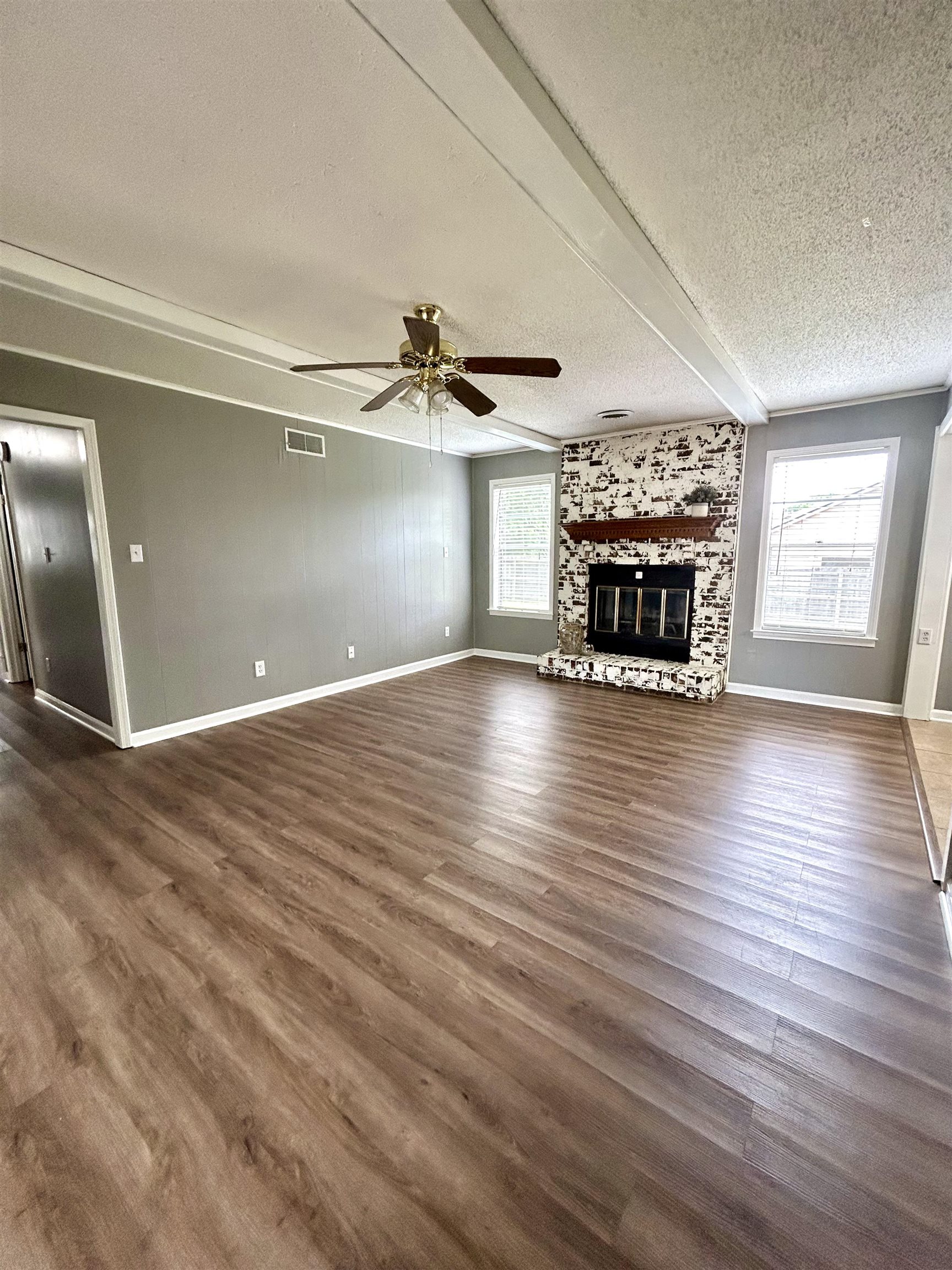 3257 Altruria Road Bartlett, TN 38134 - Photo 6 of 27 Unfurnished living room with a textured ceiling, baseboards, plenty of natural light, and a fireplace