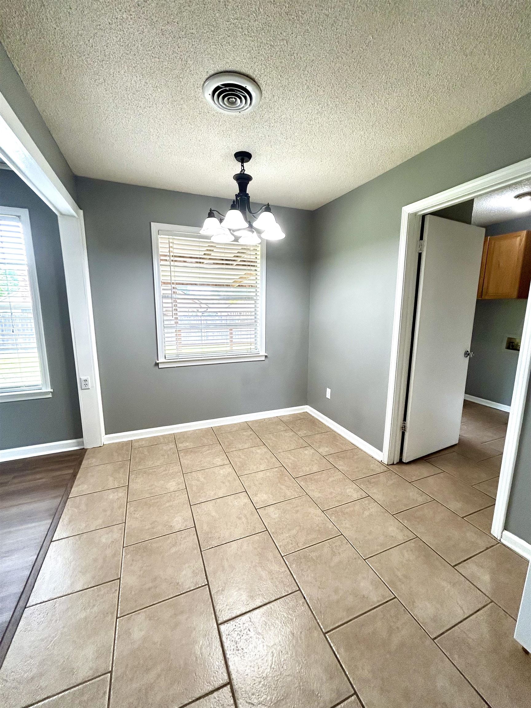3257 Altruria Road Bartlett, TN 38134 - Photo 9 of 27 Unfurnished dining area featuring light tile patterned flooring, a chandelier, a textured ceiling, and baseboards