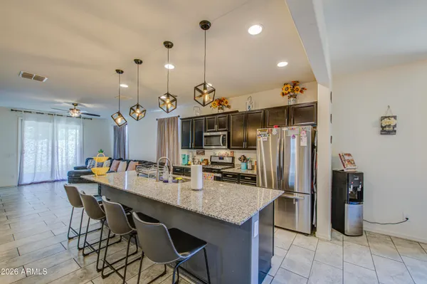 a kitchen with stainless steel appliances kitchen island granite countertop a table chairs and a refrigerator