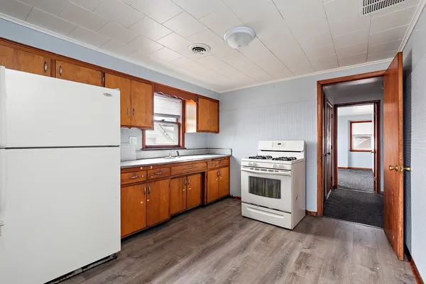 a kitchen with stainless steel appliances granite countertop a refrigerator a sink dishwasher a stove and a refrigerator with wooden floor