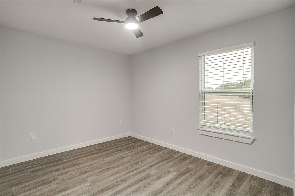 122 Kentucky Street Walnut Springs, TX 76690 - Photo 15 of 18 an empty room with wooden floor and windows