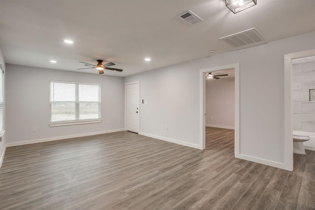 122 Kentucky Street Walnut Springs, TX 76690 - Photo 4 of 18 an empty room with wooden floor and windows