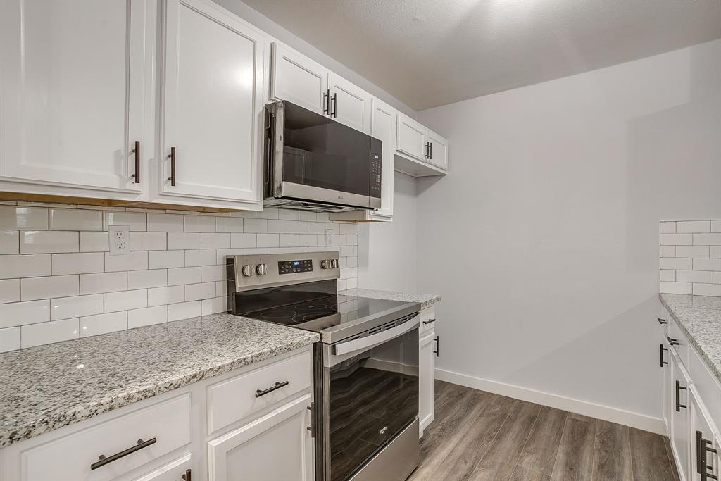 122 Kentucky Street Walnut Springs, TX 76690 - Photo 6 of 18 a kitchen with stainless steel appliances granite countertop white cabinets a microwave oven and a sink