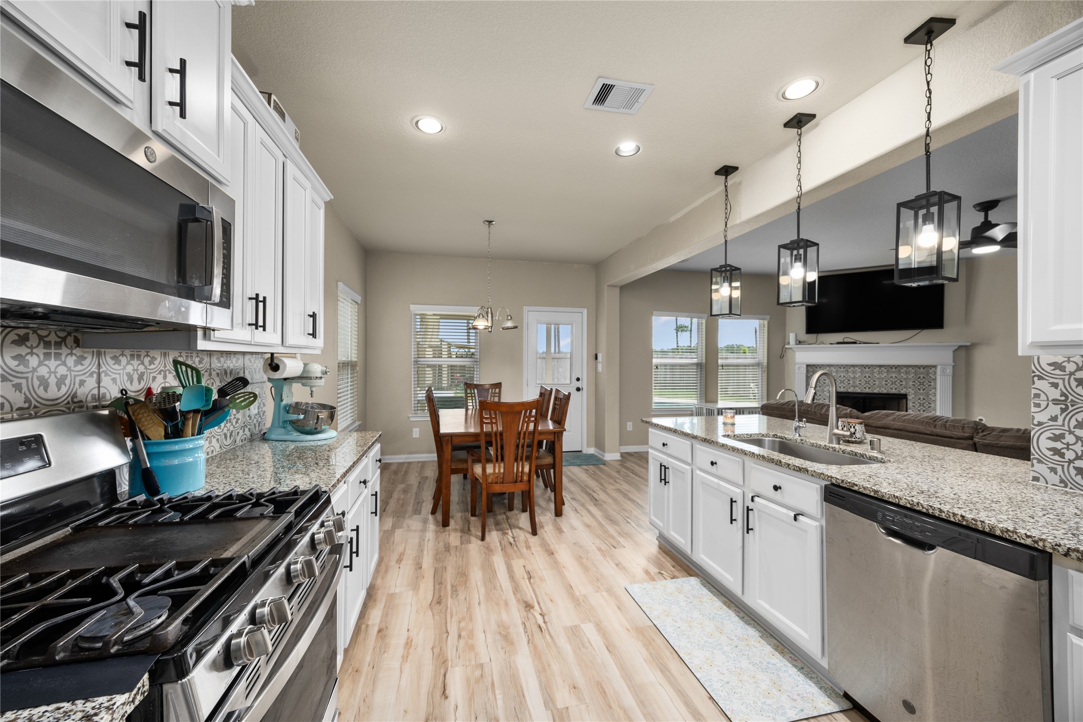 20272 Torrey Pines Lane Cleveland, TX 77327 - Photo 5 of 34 a kitchen with stainless steel appliances granite countertop a stove top oven a sink dishwasher a dining table and chairs with wooden floor