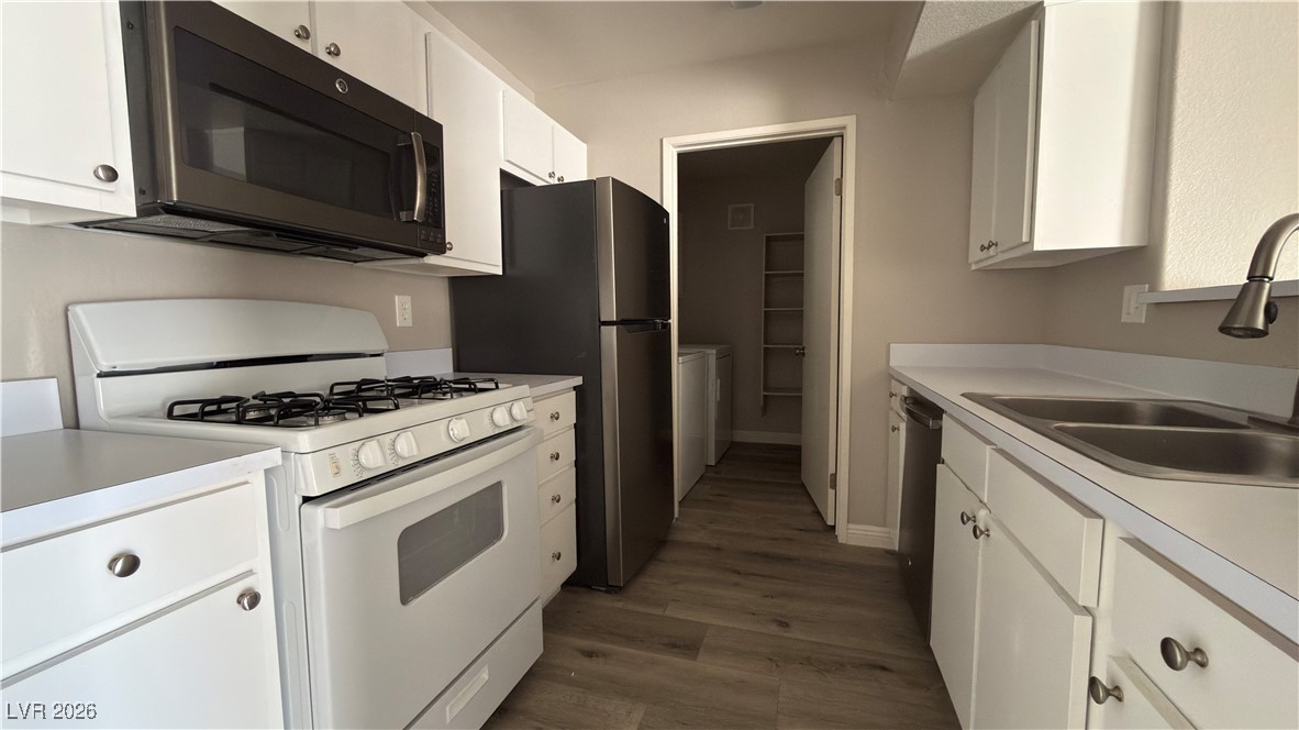 7885 West Flamingo Road, Unit 1148 Las Vegas, NV 89147 - Photo 5 of 9 Kitchen featuring white gas stove, white cabinetry, light countertops, dark wood-style floors, and dishwasher