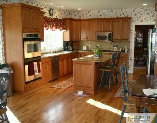 54 Springhill Road Skillman, NJ 08558 - Photo 2 of 5 a kitchen with stainless steel appliances wooden cabinets a stove top oven a sink and a dining table with wooden floor