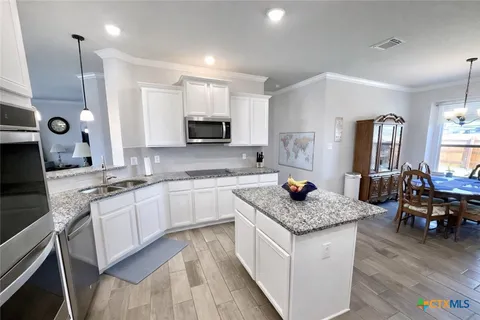 a large kitchen with stainless steel appliances kitchen island granite countertop a stove a refrigerator a sink and a microwave