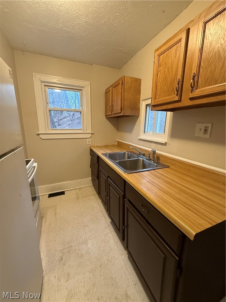 805 Carpenter Street Akron, OH 44310 - Photo 5 of 8 Kitchen with light countertops, a textured ceiling, fridge, plenty of natural light, and stove
