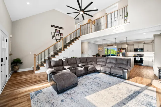 a kitchen with stainless steel appliances kitchen island granite countertop a refrigerator a stove and white cabinets with wooden floor