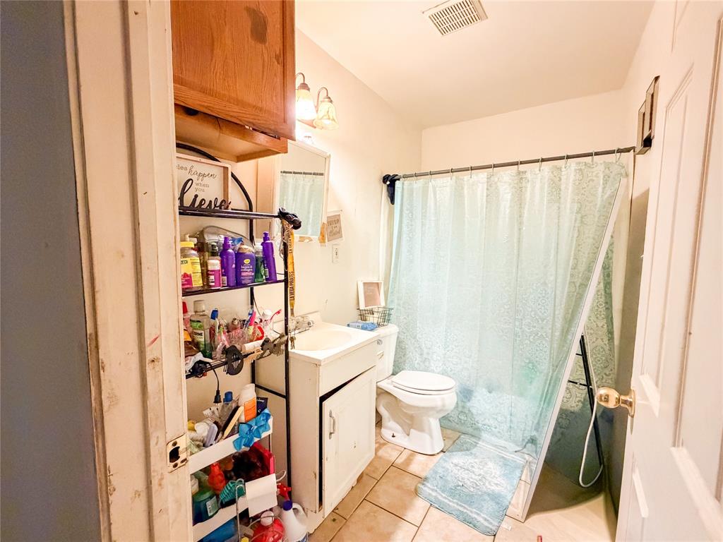 3400 Colcord Avenue Waco, TX 76707 - Photo 5 of 9 Ceramic tile flooring, vanity with integrated sink, overhead vanity lighting, built-in medicine cabinet, and a toilet