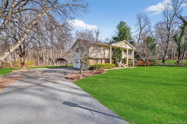 a view of a house with a big yard and large trees