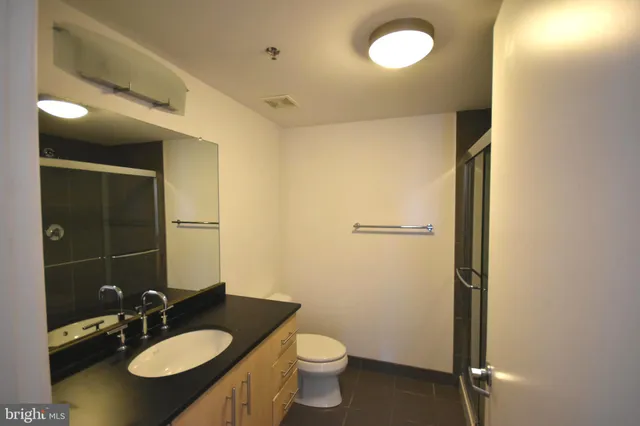 a bathroom with a granite countertop sink toilet and shower