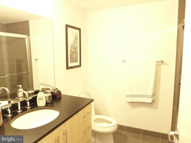 a bathroom with a granite countertop sink toilet and mirror