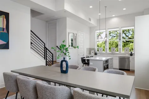 a dining room with furniture a potted plant and open kitchen view