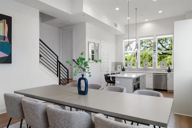 a dining room with furniture a potted plant and open kitchen view